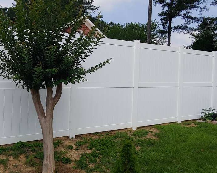 Pro vinyl fencing installation with a tree in foreground.