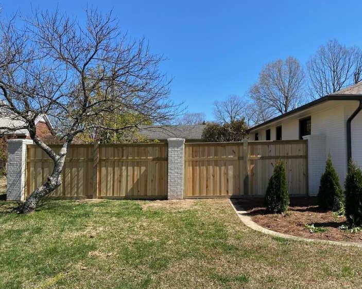 Wood privacy fence with post and tree in foreground.